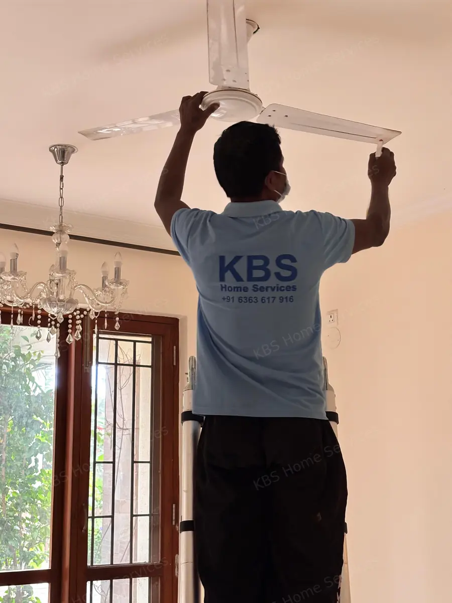 KBS technician wiping ceiling fan blades during house cleaning in Bengaluru